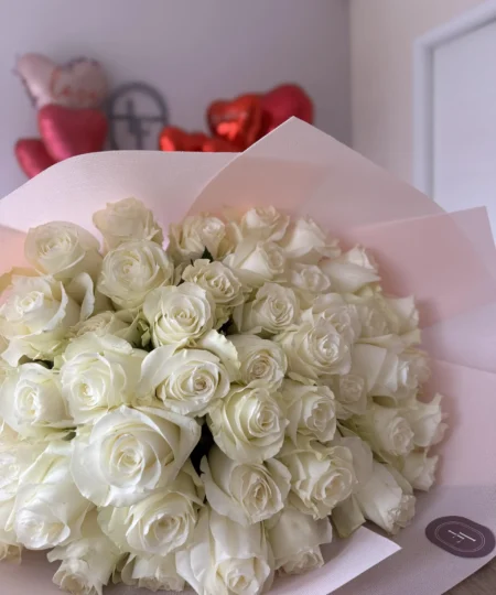 Elegant White O’Hara bouquet wrapped in soft pink paper, composed of long-stemmed ivory roses with a romantic ambiance