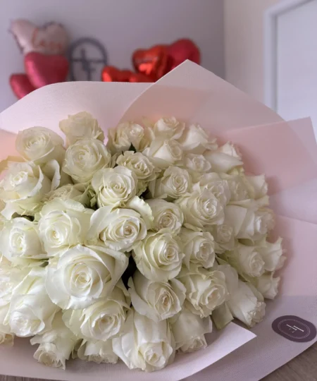 Elegancki bukiet White O’Hara owinięty w różowy papier, złożony z długich kremowych róż o romantycznym charakterze