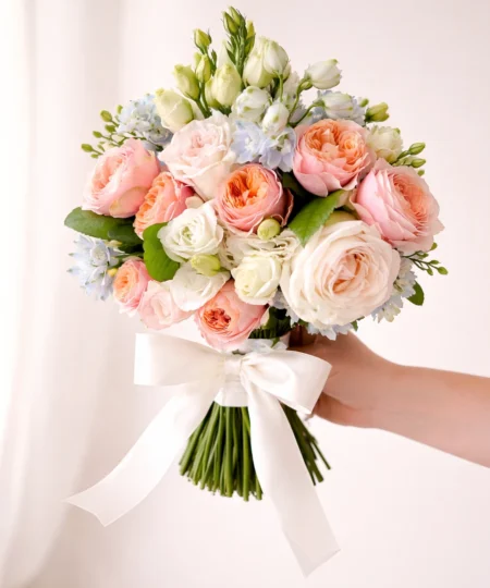 Pastelowy bukiet ślubny z róż ogrodowych, eustomy i delphinium przewiązany białą wstążką – romantyczna florystyka ślubna Lu La Fleur.